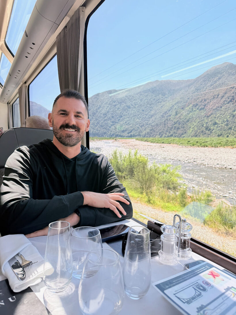 Cory at table in train car with beautiful view