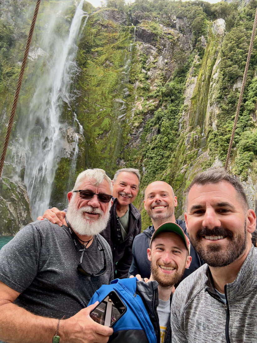 Cory and gay men travelers in front of waterfall