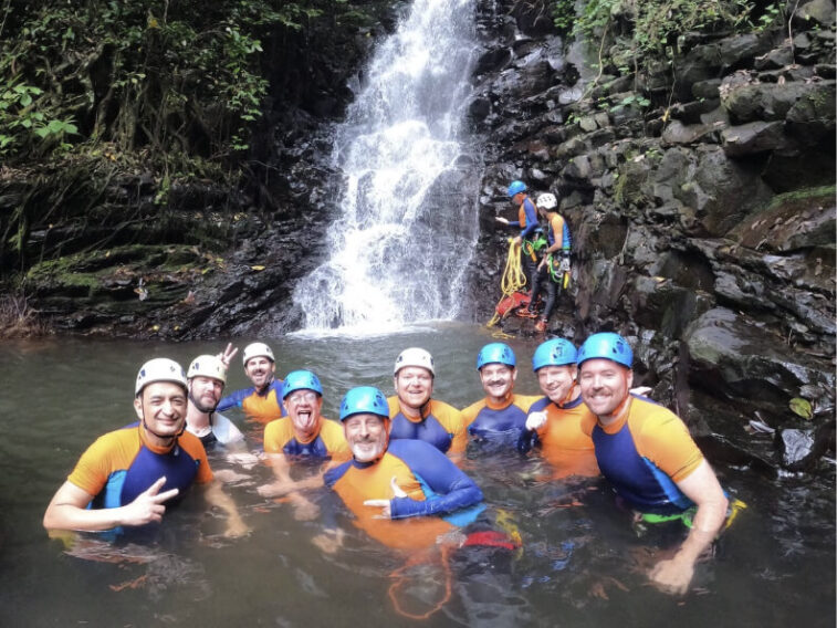 A group of gay men on an adventure in front of a waterfall