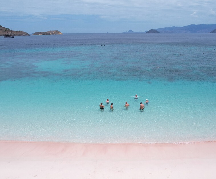 Men swimming in light blue water on a Bali beach