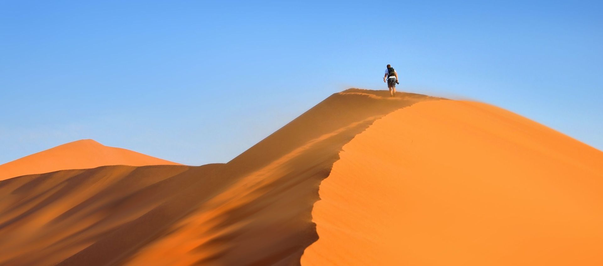 Man climbing dune in Namibia Africa - gay travel - gay trip - Pivot Trip